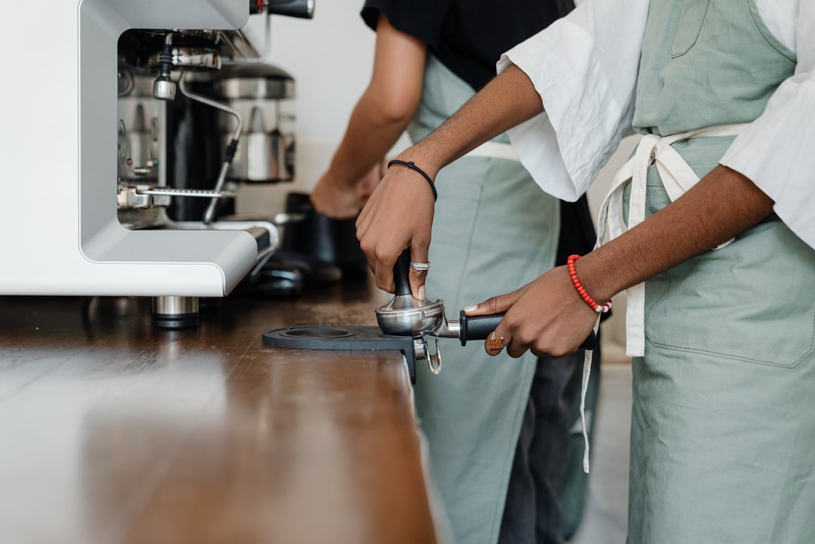 Crop barista preparing coffee in modern cafe